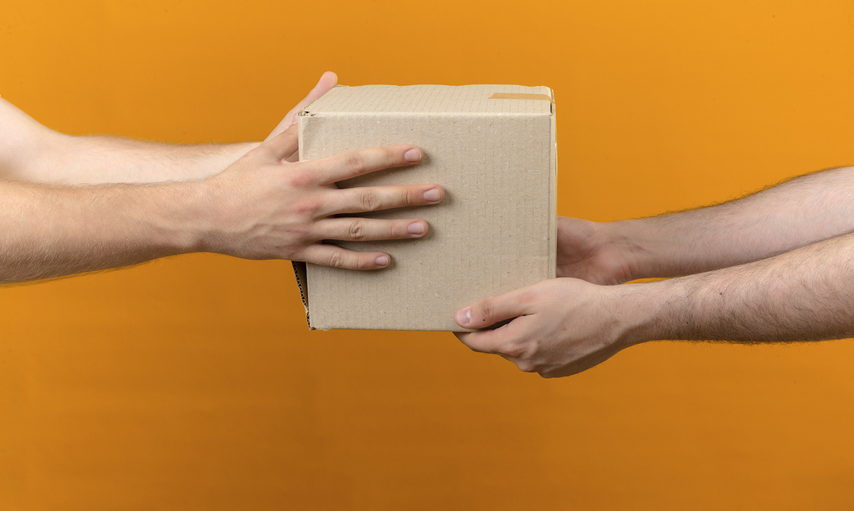 delivery man giving box package to customer over isolated orange background side view